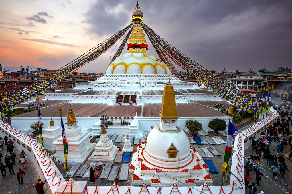 Boudhanath Stupa at sunset adorned with vibrant prayer flags and sacred stupas in Kathmandu