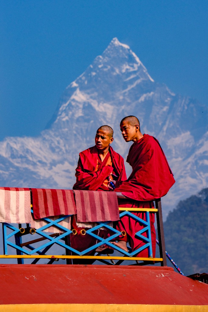 Himalayan Buddhist monks in maroon robes overlooking Machhapuchhre peak